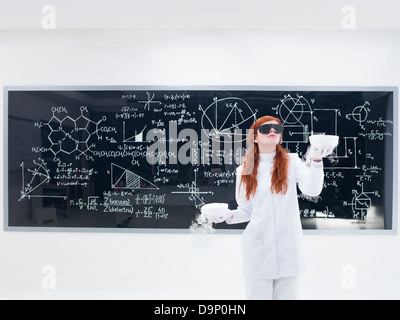 Vue générale d'une jolie fille étudiant dans un laboratoire de chimie portant des lunettes noires et la réalisation d'une expérience avec un gaz magique bl Banque D'Images