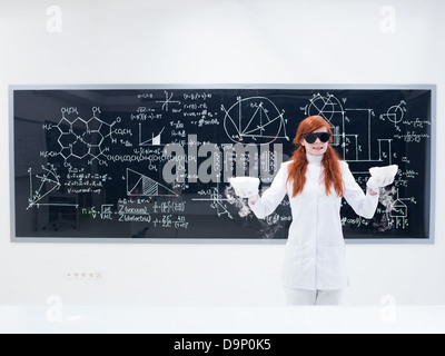 Vue générale d'une jolie fille étudiant dans un laboratoire de chimie portant des lunettes noires et la réalisation d'une expérience magique et looki gaz Banque D'Images