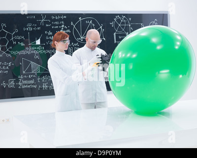Vue générale de l'enseignant et l'élève dans un laboratoire de chimie de la numérisation d'un ballon vert et un tableau noir sur l'arrière-plan Banque D'Images
