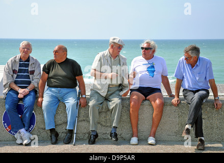 Cinq vieux hommes assis sur un mur près de la mer, à Le Tréport, sur la côte nord de la France, l'Europe. Banque D'Images