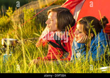 Jeune couple couché dans la tente de camping avec le coucher du soleil Banque D'Images