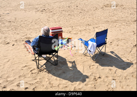 Homme plus âgé assis sur une chaise, la station d'été Banque D'Images