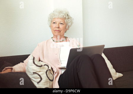 Cheerful senior dame qui sent une fleur à l'intérieur Banque D'Images