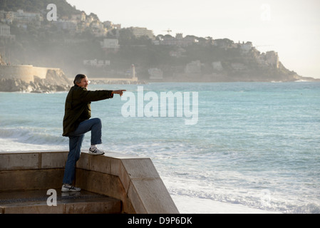 Un homme qui regarde la mer et vue de la Promenade des Anglais à Nice France en Décembre Banque D'Images