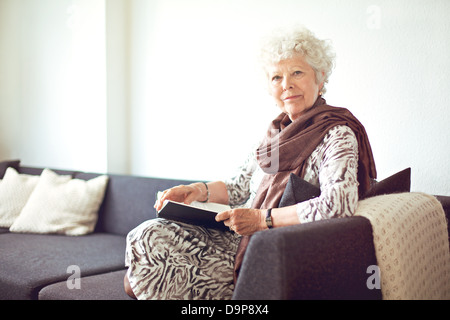 Grand-mère détendue assis sur le canapé à la maison Banque D'Images