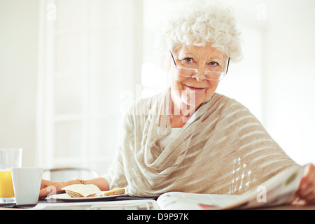 Happy senior femme lisant son journal du matin Banque D'Images