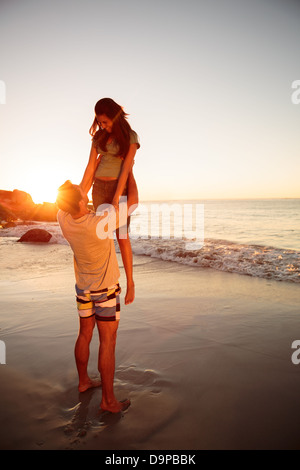 L'homme en soulevant sa petite amie sur la plage Banque D'Images