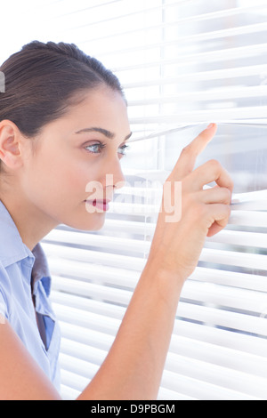 Brunette businesswoman peeking through un store Banque D'Images