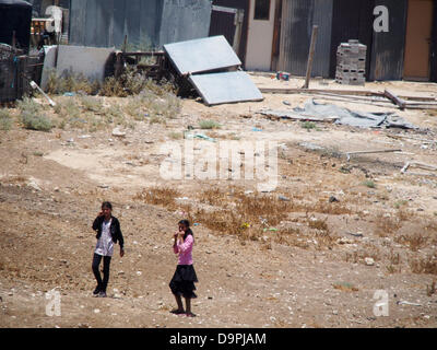 Israël. 24 Juin, 2013. Les jeunes enfants bédouins 'flirter' avec l'appareil comme ils courent pieds nus et jouer dans le village bédouin non reconnu d'Al Monsieur. Le village souffre de l'abandon des dernières décennies. Les écoles sont situées à une distance de 7 Km. Le Prawer-Begin proposition vise à réglementer le règlement des Bédouins du Néguev et devrait passer à la Knesset ce soir à la première de trois lectures en dépit de l'opposition bédouins. Credit : Alon Nir/Alamy Live News Banque D'Images