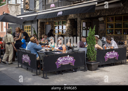 Les clients s'asseoir à la terrasse d'un café de la Sylvia's restaurant sur Lenox Avenue dans le quartier de Harlem à New York Banque D'Images