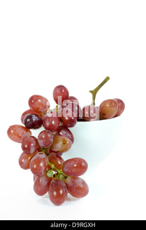 Close up branche de raisin rouge dans un bol blanc sur fond blanc. Banque D'Images