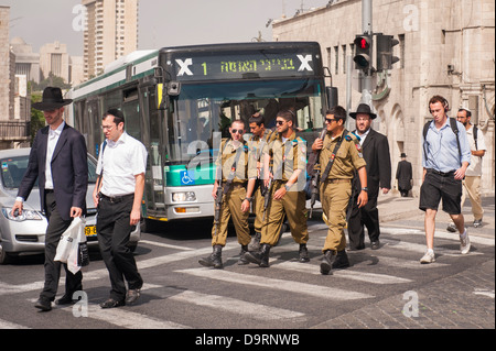 Israël Jérusalem moderne des soldats armés hors-service Zahal FDI sur passage piétons par la compagnie Egged coach juifs orthodoxes touristes scène de rue feux piétons Banque D'Images