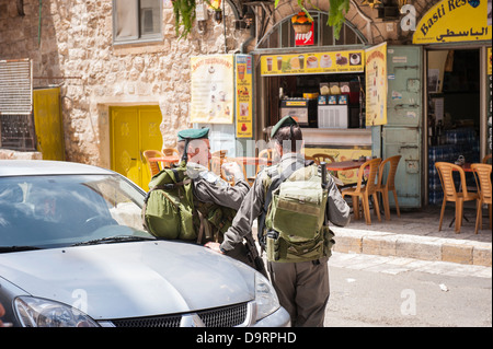 Israël Jérusalem Vieille ville quartier arabe musulmane Via Dolorosa deux soldats des forces armées 2 en uniforme s'appuyant sur chattiing voiture Restaurant Cafe Basti Banque D'Images