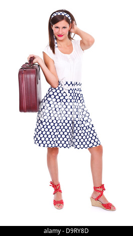 Jeune femme brune en robe de style rétro avec une valise, à la recherche d'appareil photo. Isolées. Banque D'Images