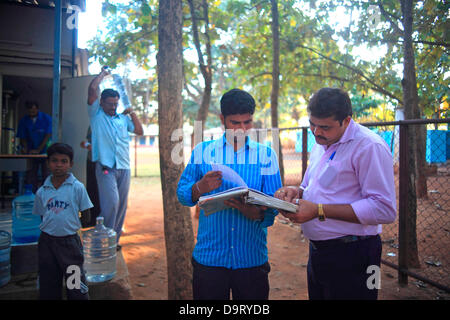 24 nov., 2012 - Bangalore, Karnataka, Inde - un habitant du village Hebbagodi porte accueil bidons d'eau potable fournie par les eaux Naandi. Grandes entreprises multinationales ciblent de plus en plus bas de la pyramide, les pauvres, dans les pays en développement comme l'Inde à conduire la croissance future et les profits. (Crédit Image : © Subhash Sharma/ZUMAPRESS.com) Banque D'Images