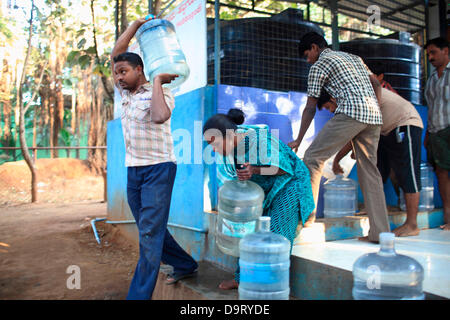 24 nov., 2012 - Bangalore, Karnataka, Inde - les villageois de village Hebbagodi apporte à la maison des boîtes de l'eau potable fraîche fournis par Naandi Eaux. Grandes entreprises multinationales ciblent de plus en plus bas de la pyramide, les pauvres, dans les pays en développement comme l'Inde à conduire la croissance future et les profits. (Crédit Image : © Subhash Sharma/ZUMAPRESS.com) Banque D'Images