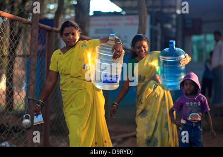 24 nov., 2012 - Bangalore, Karnataka, Inde - les femmes de village Hebbagodi transporter accueil bidons d'eau potable fraîche fournis par Naandi Eaux. Grandes entreprises multinationales ciblent de plus en plus bas de la pyramide, les pauvres, dans les pays en développement comme l'Inde à conduire la croissance future et les profits. (Crédit Image : © Subhash Sharma/ZUMAPRESS.com) Banque D'Images