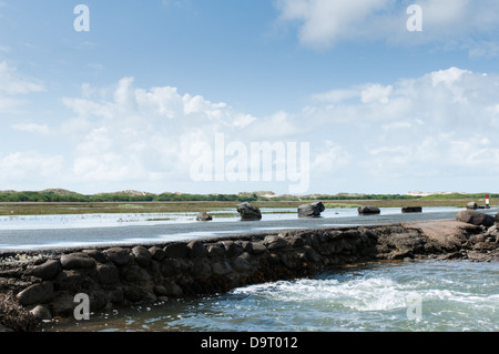 Le pont-jetée de Shell Island est couverte par l'eau de mer à marée haute. La vague s'écoule à travers une série de tuyaux de vidange. Banque D'Images