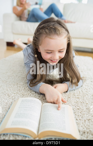 Girl reading book avec sa mère lire le journal Banque D'Images