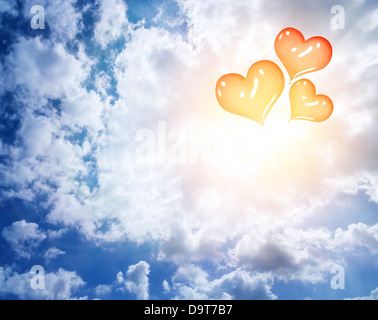 Ballons gonflables en forme de coeur rouge en bleu ciel nuageux, résumé contexte romantique, lune de miel, concept d'amour Banque D'Images