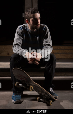 Skater sitting on steps dans le skate park Banque D'Images