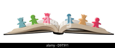 Figurines colorées sur le dessus d'un livre ouvert isolé sur fond blanc Banque D'Images