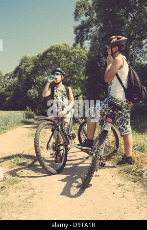 Deux adolescents avec des vélos de détente sur un vélo en journée ensoleillée, couleurs rétro Banque D'Images