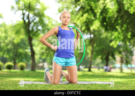 Athlète féminin sur un tapis d'exercice tenant un cerceau dans un parc Banque D'Images