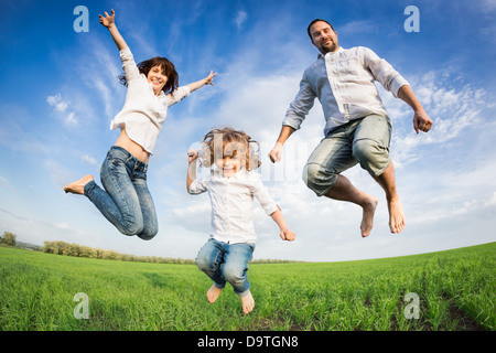 Happy active family jumping in green field. Concept de vacances d'été Banque D'Images