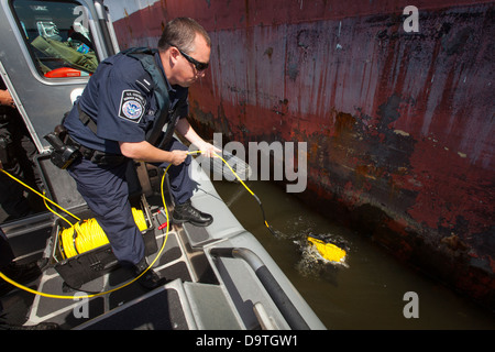 Les agents des douanes et de la protection des frontières (CBP) des États-Unis déploient un robot sous-marin sous un navire au port de Philadelphie. Cette opération, menée en collaboration avec la police d’État de Pennsylvanie, vise à détecter les anomalies sous la surface de l’eau. Banque D'Images