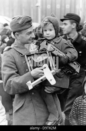 Un soldat allemand de Wehrmacht à bord de la fourrure transporte son enfant autour du marché de Noël dans le Berlin Lustgarten en hiver 1942. Fotoarchiv für Zeitgeschichte Banque D'Images