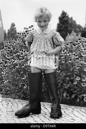 Une fille porte les bottes de son père qui, en tant que soldat de la Wehrmacht allemande, est en colère contre sa famille. Emplacement inconnu. La propagande nationale socialiste! A partir du 17 octobre 1940 au dos de la photo: 'Mrs Seven-League Boots... Dans les deeps les plus profonds des 'jackbots' du père. Fotoarchiv für Zeitgeschichte Banque D'Images