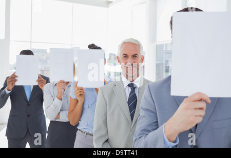 L'équipe d'affaires couvrant le visage avec du papier blanc à l'exception d'une Banque D'Images