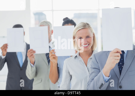 L'équipe d'affaires couvrant le visage avec du papier blanc à l'exception d'une femme Banque D'Images