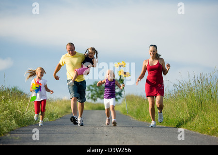 Famille avec trois enfants qui courent vers le bas d'une colline Banque D'Images