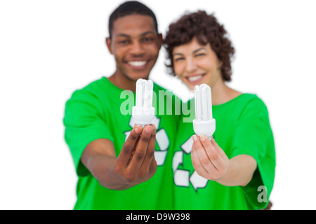 Cheerful activists holding energy saving light bulbs Banque D'Images