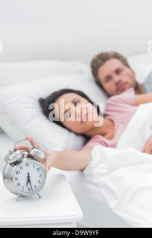 Tired woman arrêt de l'alarme réveil Banque D'Images