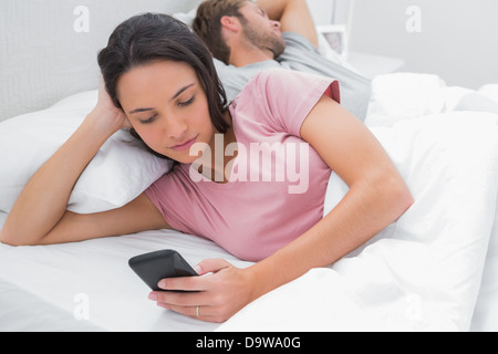 Femme textos pendant que son partenaire est en train de dormir Banque D'Images