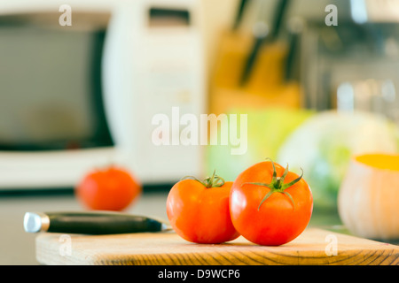 La préparation des aliments frais sur le banc de la cuisine, avec des tomates, courgettes et autres légumes à l'arrière-plan Banque D'Images