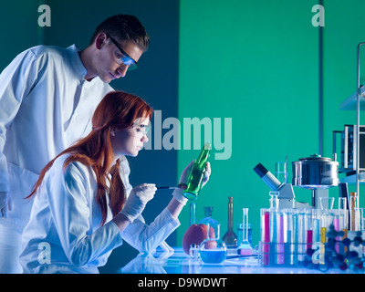 Vue latérale des deux scientifiques d'investigation de la bouteille, la prise des empreintes digitales dans un laboratoire Banque D'Images