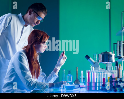 Vue latérale des deux experts judiciaires à la race blanche dans une cartouche rouge avec empreintes digitales sur, dans un laboratoire Banque D'Images