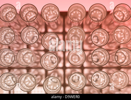 Vue de dessus, la macro d'un banc d'essai de laboratoire avec des tubes à essai en verre rempli de liquide sur un fond rouge Banque D'Images