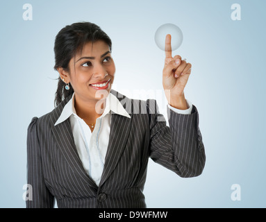 Indian businesswoman finger touching virtual d'écran bouton. Sourire heureux isolé sur fond bleu. Modèle féminin asiatique de l'Inde. Banque D'Images