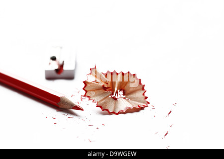 Aiguisé crayon rouge et copeaux avec aiguiseur hors focus Banque D'Images