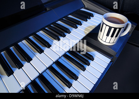 Un clavier électrique manuel deux et une tasse de thé (lait, pas de sucre). Banque D'Images