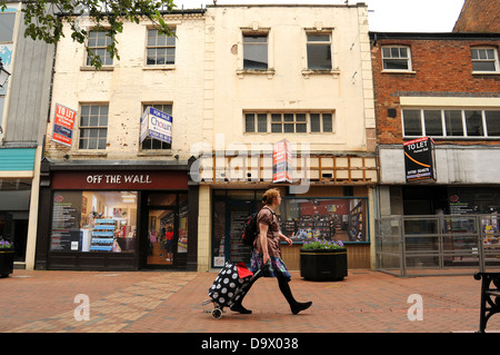 Un nouveau client marche dernières boutiques vides dans High Street, Rugby, Warwickshire. Banque D'Images