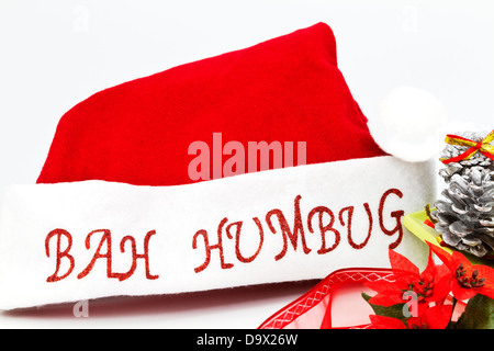 Le rouge et le blanc Santa Claus hat placé avec l'argent des pommes de pin, des rubans et des fêtes poinsettia fleurs sur fond blanc. Banque D'Images