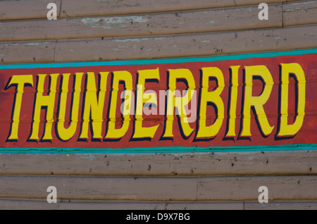 Le mot 'Thunderbird' est peint sur l'extérieur d'un bâtiment de rondins dans des couleurs vives. Banque D'Images