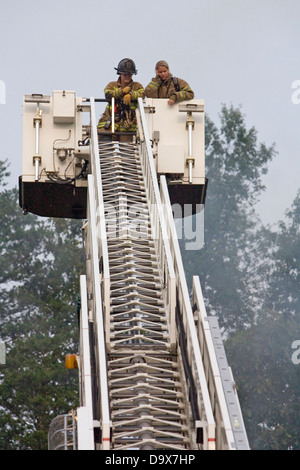 Deux soldats du feu en haut d'une échelle de la benne pendant la lutte contre l'incendie d'une maison. Banque D'Images