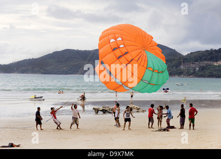 PATONG Beach, Phuket, Thaïlande 14 AOÛT 2011 : un groupe d'opérateurs du parachute ascensionnel préparer un client pour un tour. Banque D'Images